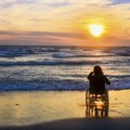Sunset, makes sightseeing on the beach a woman on wheelchair stock photo