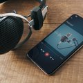 Earphone and cellphone with screen showing the word podcast