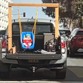 A baby swinging on a contraption at the back of a van
