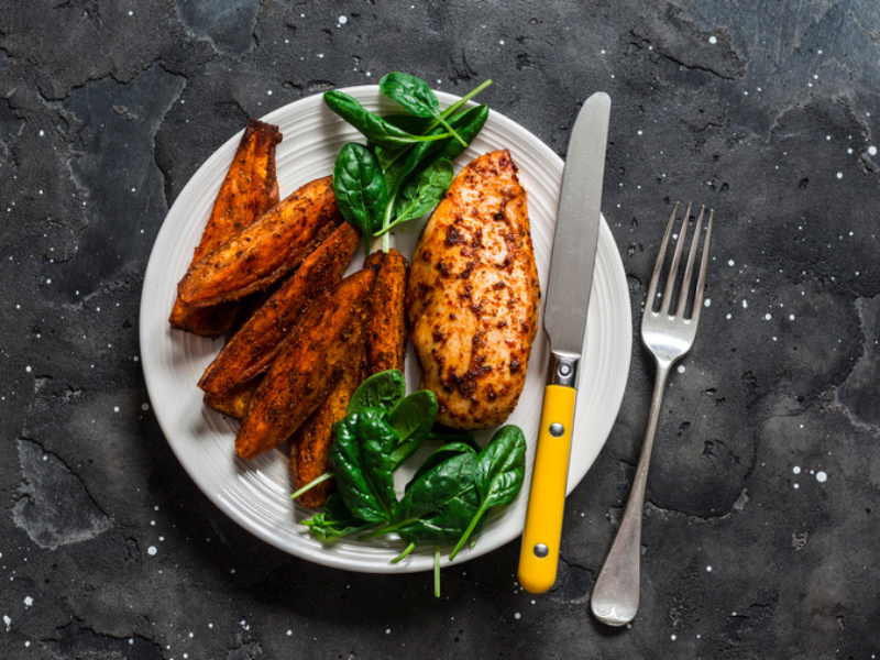 A baked chicken breast with sweet potato and spinach