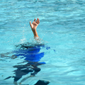 A child holding their hand up in a swimming pool in need of help