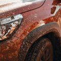 A close up of a Toyota Hilux headlamp that has mud splashes