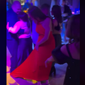 A man steps on a ladys red dress at a dance party