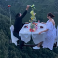 A couple dining on a zipline above a high cliff