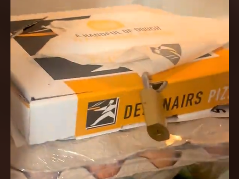 A Debonairs pizza box inside a fridge with a lock