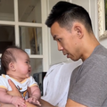 A father holds his baby on his lap and talks to him