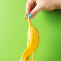 A female hand with colourful manicure holding a peel of banana