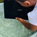 A girl picks up an Acer laptop from a bucket of water