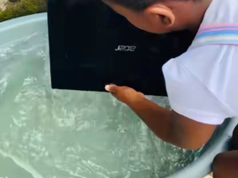 A girl picks up an Acer laptop from a bucket of water