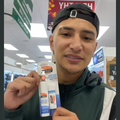 A guy holding up a lip product that he found at a store
