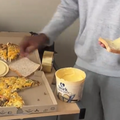 A guy holds a buttered slice of bread with pizza