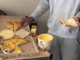 A guy holds a buttered slice of bread with pizza