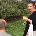 A guy proposes to his girlfriend at an apple farm