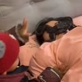 A little boy places a frog on his mothers face while she is asleep