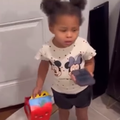 A little girl holding a takeout box and a smartphone