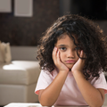 A little girl looks bored as she holds her face in her hands