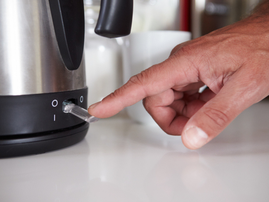 A man flicks the switch to boil a kettle