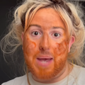 A man imitates a woman applying her makeup using food items