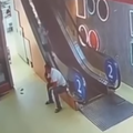 A man is on the phone while his child goes up the side of an escalator