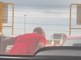 A man leans into a car window to chat to a motorist at the toll plaza