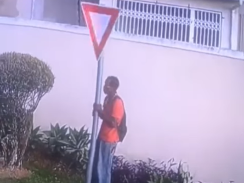 A man pulls out a road sign from the ground