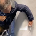 A man trying to plug his phone charger into the wall at an airport
