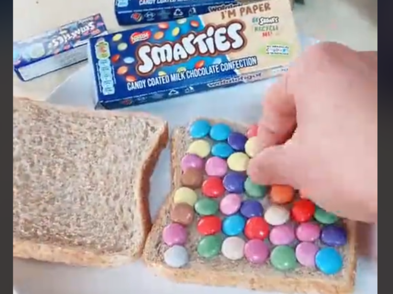 A person making a sandwich with chocolate buttons