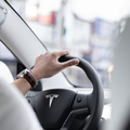 A person wearing a face mask driving a tesla