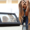 A sad woman after a breakup holds her head with shattered photo frame