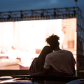 A sihouetted view of a couple watching a movie at a drive in