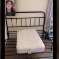 A small bed lying on an adult sized bed frame