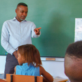 A teacher engages with students in classroom during the lesson