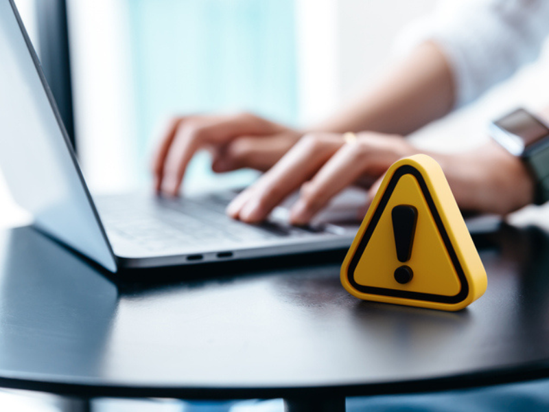 A warning sign placed on a table while working on a laptop