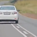 A white Toyota driving in the middle of the road