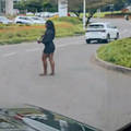 A woman dressed in black standing on a busy road in Umhlanga