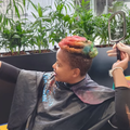 A woman looking at her spraypainted hair in a mirror at CANSA Shavathon