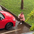 A woman sitting in the rain looking at her new car