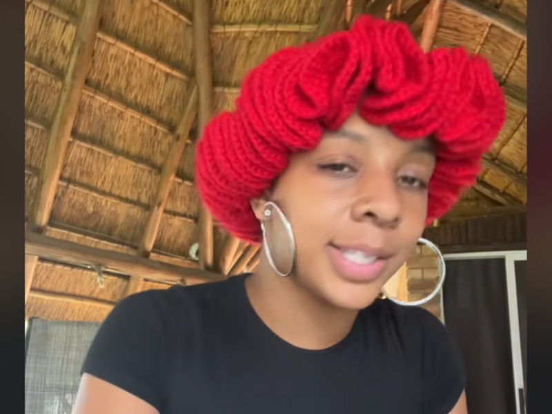 A woman wearing a red knitted hair bonnet with large hoop earrings