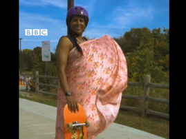 A woman wearing a sari standing with her skateboard