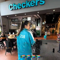 A woman wearing a turquoise coloured Squid Games tracksuit entering Checkers