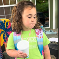 A young American girl stands wearing her backpack