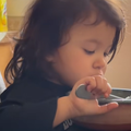A young child eats her food out of a bowl at the dinner table