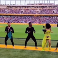 A young dancer who looks like Tyla dances with others at a soccer stadium
