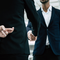 An employee crossing his fingers at his back and shakes hands with manager