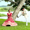 An Indian bride sits on a tree while the groom dusts his shoe