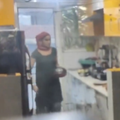An Indian woman holds a container inside a kitchen