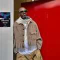 Black Coffee leaning against a red door