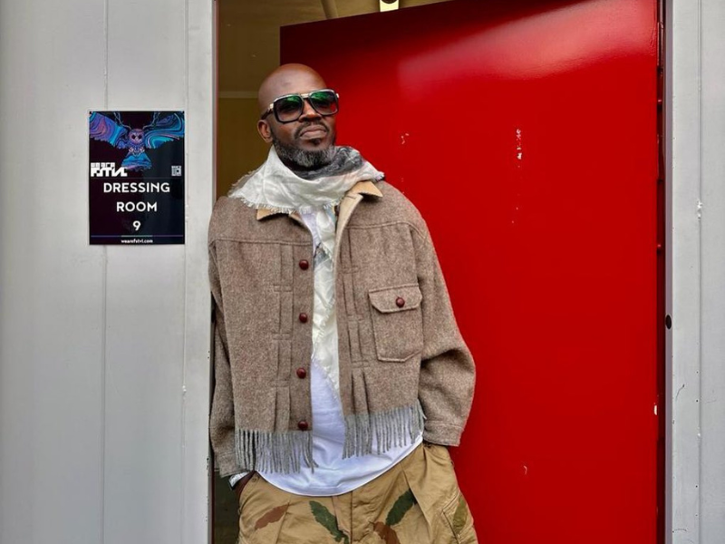 Black Coffee leaning against a red door