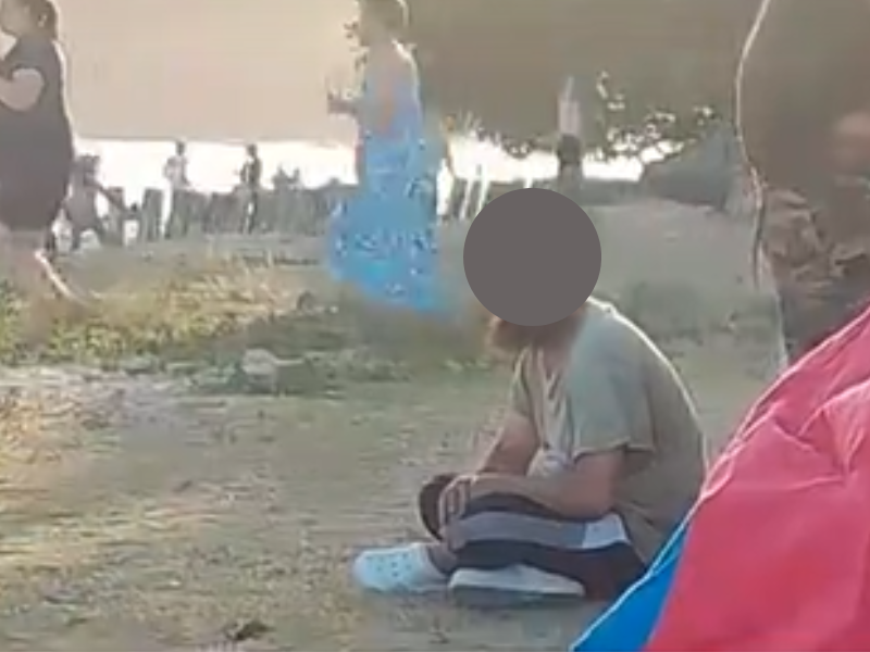 A man with a beard stares at a family at the beach