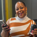 Carol Ofori standing inside the studio with a coffee and her phone